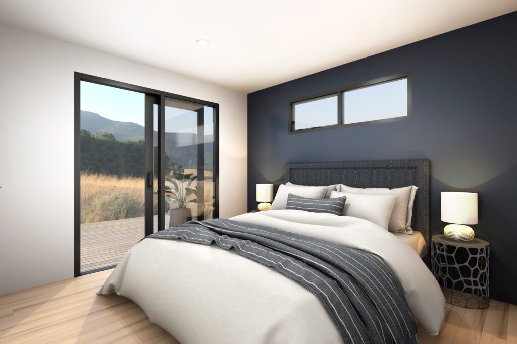 Modern bedroom interior in a one-bedroom portable home NZ with sliding glass doors opening to a deck and scenic view — compact, stylish small home by Paragon Portables.