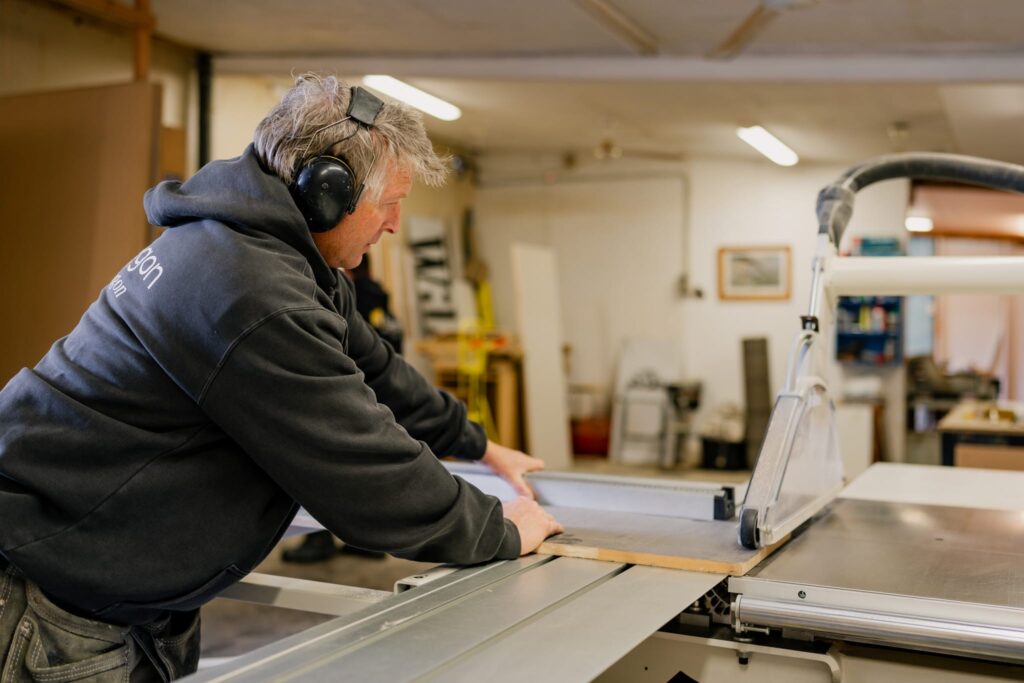 Paragon Portables builder cutting timber on table saw inside workshop in Canterbury, NZ.