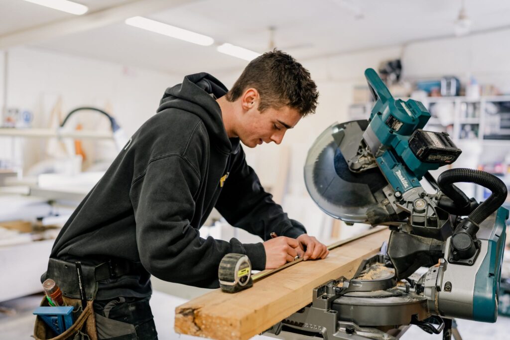 Apprentice builder marking timber in Paragon Portables workshop, showcasing home builders NZ for relocatable homes.