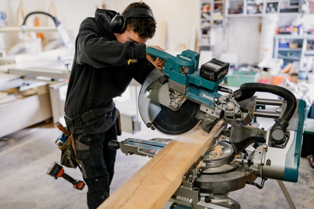 Builder using drop saw to cut timber for small houses NZ and portable homes NZ by Paragon Portables.