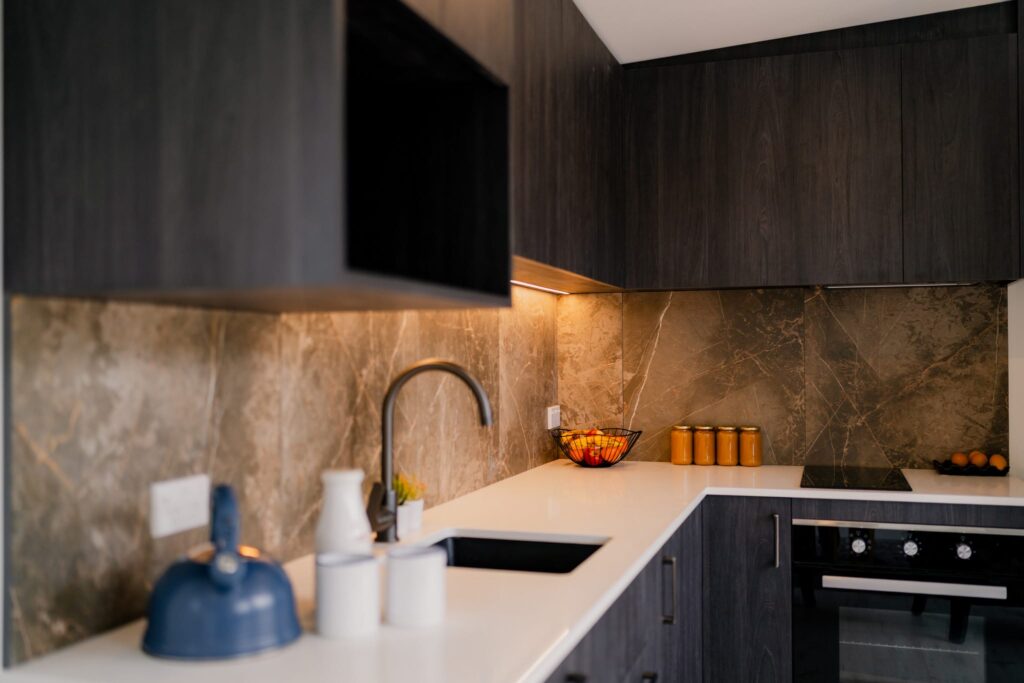 Modern compact kitchen inside a new portable home NZ featuring marble splashback, dark cabinetry and eco-friendly home design — perfect for small homes and tiny houses in New Zealand.